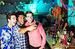 Men taking self-portraits with camera phone at party