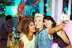 Women taking self-portrait with camera phone at party