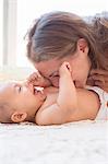 Mother blowing raspberries on baby's stomach