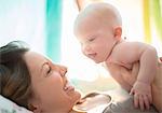 Mother holding baby girl on bed