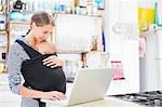 Mother with baby boy using laptop in kitchen