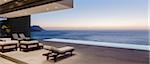 Modern patio and infinity pool overlooking ocean at sunset