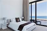 Bed and lamps in modern bedroom overlooking ocean