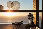 Patio of modern house overlooking ocean at sunset