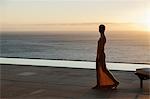 Woman looking at ocean from modern patio at sunset