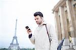 Businessman using cell phone by Eiffel Tower, Paris, France