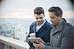 Businessmen using digital tablet with Paris, France in background