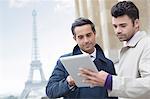 Businessmen using digital tablet near Eiffel Tower, Paris, France