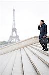 Businessman talking on cell phone on steps near Eiffel Tower, Paris, France