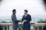 Businessmen shaking hands at railing overlooking Paris, France