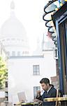 Businessman working at sidewalk cafe near Sacre Coeur Basilica, Paris, France