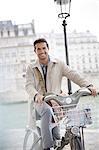 Businessman on bicycle along Seine River, Paris, France