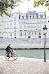 Man riding bicycle along Seine River, Paris, France