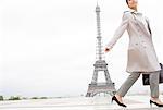 Businesswoman walking past Eiffel Tower, Paris, France