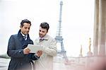 Businessmen using digital tablet near Eiffel Tower, Paris, France