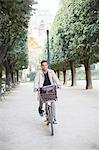 Businessman riding bicycle in park, Paris, France