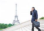 Businessmen on cell phone on steps near Eiffel Tower, Paris, France