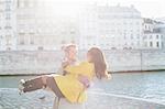 Man holding girlfriend along Seine River, Paris, France