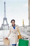 Woman carrying shopping bags by Eiffel Tower, Paris, France