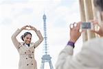 Man photographing girlfriend in front of Eiffel Tower, Paris, France