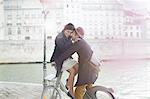 Couple hugging on bicycle along Seine River, Paris, France