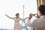 Man photographing girlfriend in front of the Eiffel Tower, Paris, France