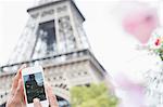 Woman photographing Eiffel Tower with camera phone, Paris, France
