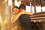 Woman with jewelry box hugging man in restaurant