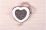 White heart shaped frame filled with chia seeds, on white oak wood.