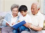 grandparents and grandson reading a book together.