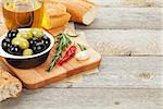 Italian food appetizer of olives, bread and spices on wooden table background with copy space