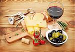Red wine with cheese, olives, bread, vegetables and spices on wooden table