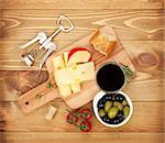 Red wine with cheese, bread, olives and spices. Over wooden table background. View from above