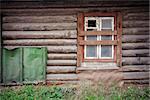 Weathered log house wall with boarded up window