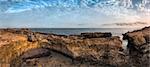 Sunset over the Sea and Rocky Coast with Ancient Ruins