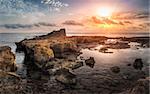 Sunset over the Sea and Rocky Coast with Ancient Ruins