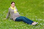 Beautiful pregnant woman relaxing in the park on the green grass
