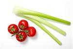 Top view of bunch of fresh tomatoes and celery sticks on white background