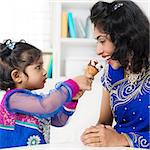 Indian girl feeding her mum ice-cream. Asian family living lifestyle at home.