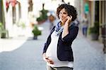 Happy people and lifestyle with pregnant woman talking with cell phone in city street