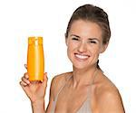Portrait of happy young woman showing bottle of sun screen creme