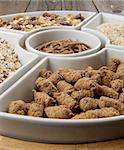 Bran, Muesli with Fruits and Oat Flakes in White Plates closeup on Wooden background