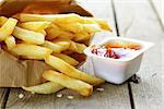 Traditional potatoes French fries with salt on wooden background