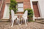 Set of white garden table and chairs on patio outside rural house