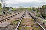 View down railway track over bridge in english rural countryside with overcast sky