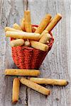 Bread Sticks with Sesame Seeds in Red Wicker Basket on Rustic Wooden background