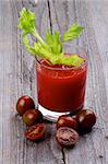 Brown Cherry Tomatoes Full Body and Halves with Glass of Freshly Squeezed Tomato Juice with Celery isolated on Wooden background