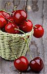 Ripe Sweet Cherries in Green Wicker Basket closeup on Rustic Wooden background