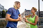 Two adult runners taking a break on city footbridge