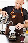 Male barista pouring boiling water into coffee filter